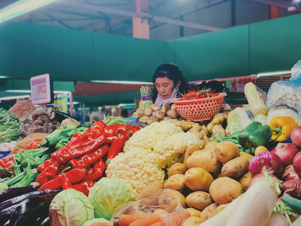 girl in red and white dress standing beside yellow and red fruit display