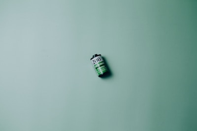 A single roll of film is placed against a textured green background. The film roll displays the number 200 and consists of black, white, and green colors.