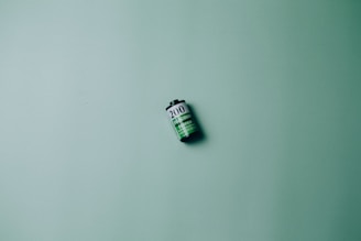A single roll of film is placed against a textured green background. The film roll displays the number 200 and consists of black, white, and green colors.