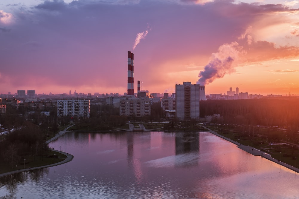 body of water near city buildings during sunset