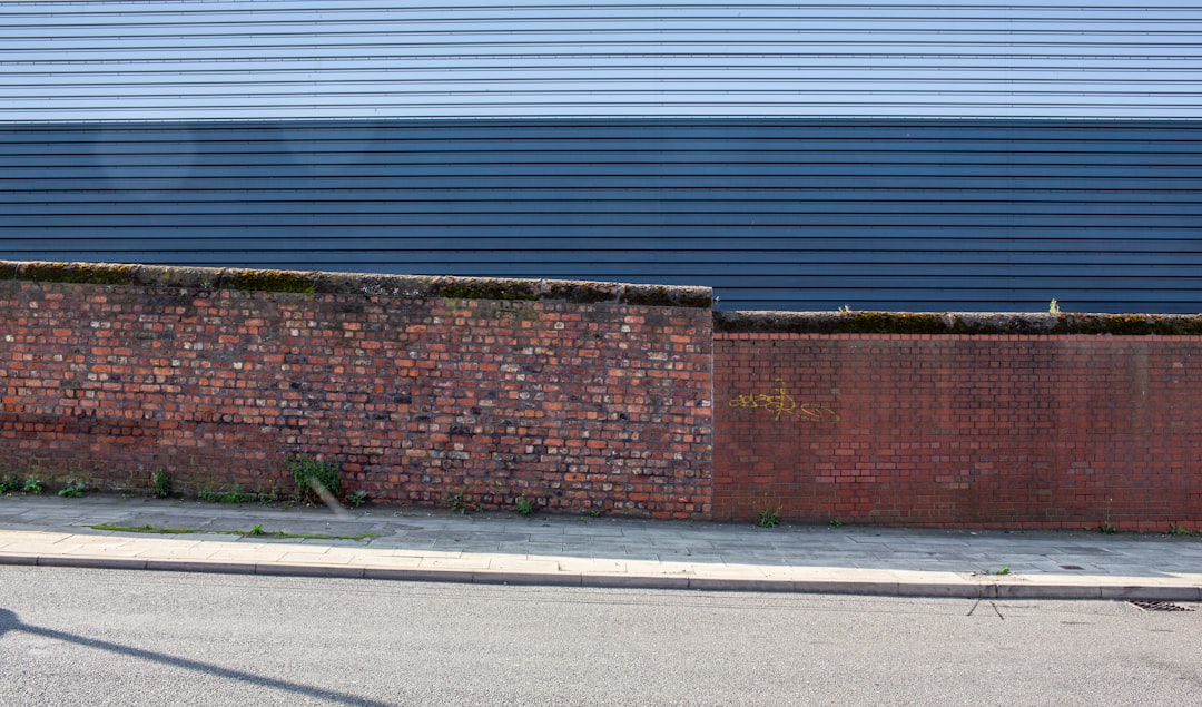 brown brick wall beside gray asphalt road during daytime