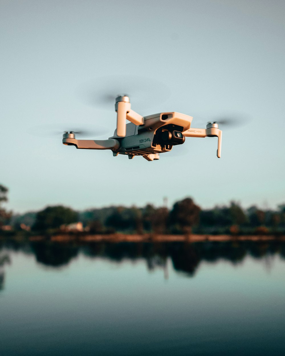 white and orange drone flying over the lake during daytime