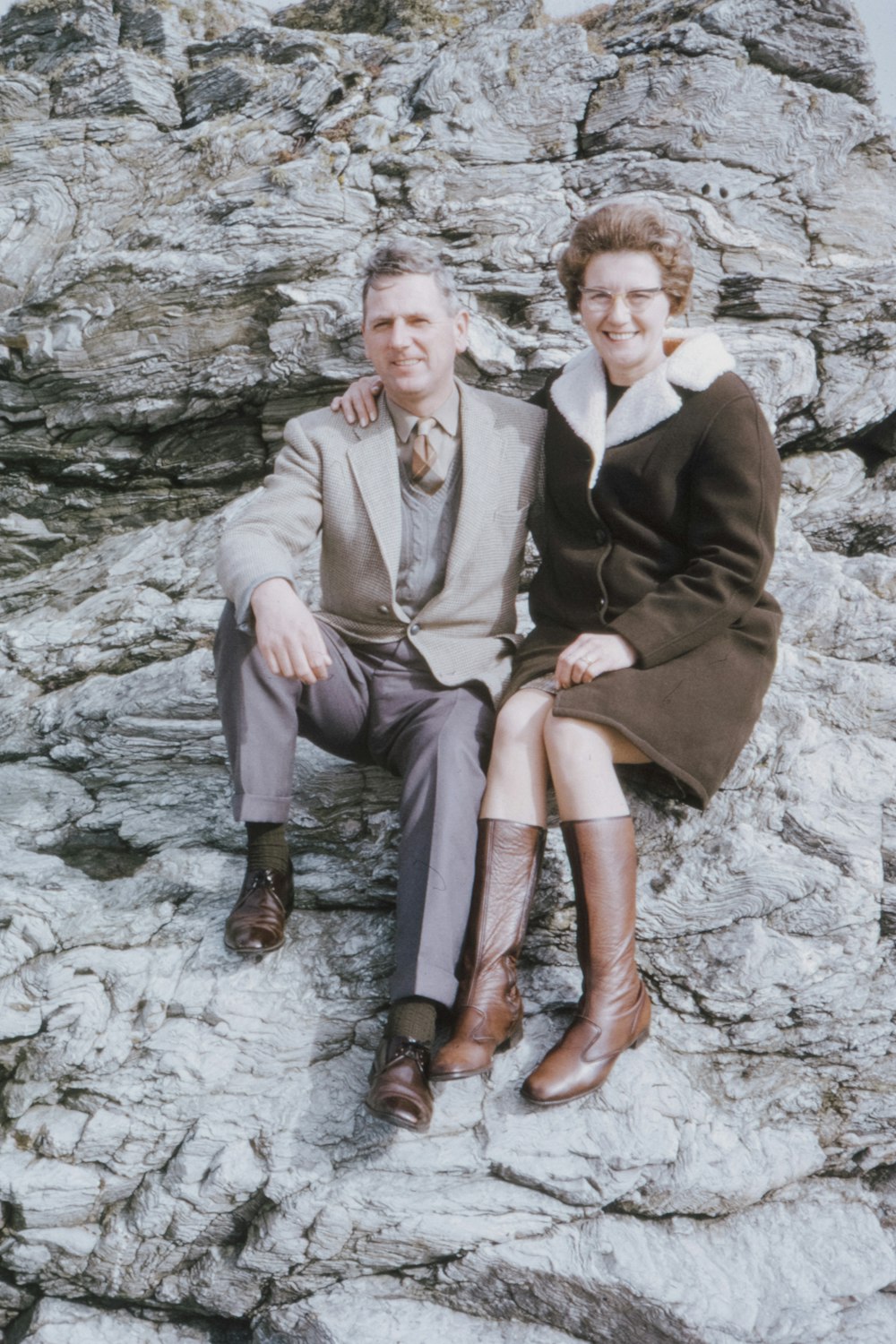 man and woman sitting on rock beside river