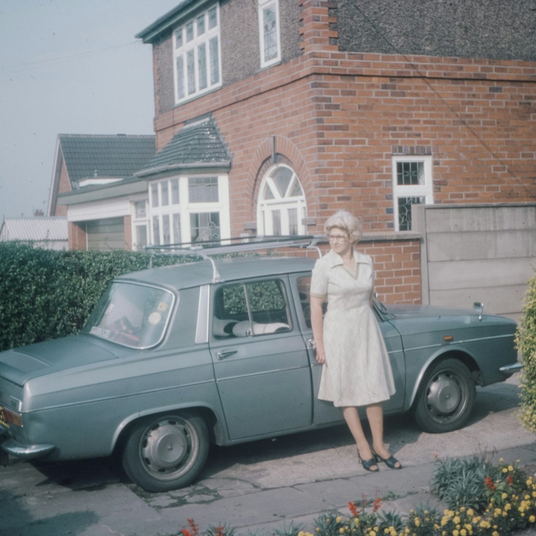 woman in white long sleeve dress standing beside green car during daytime