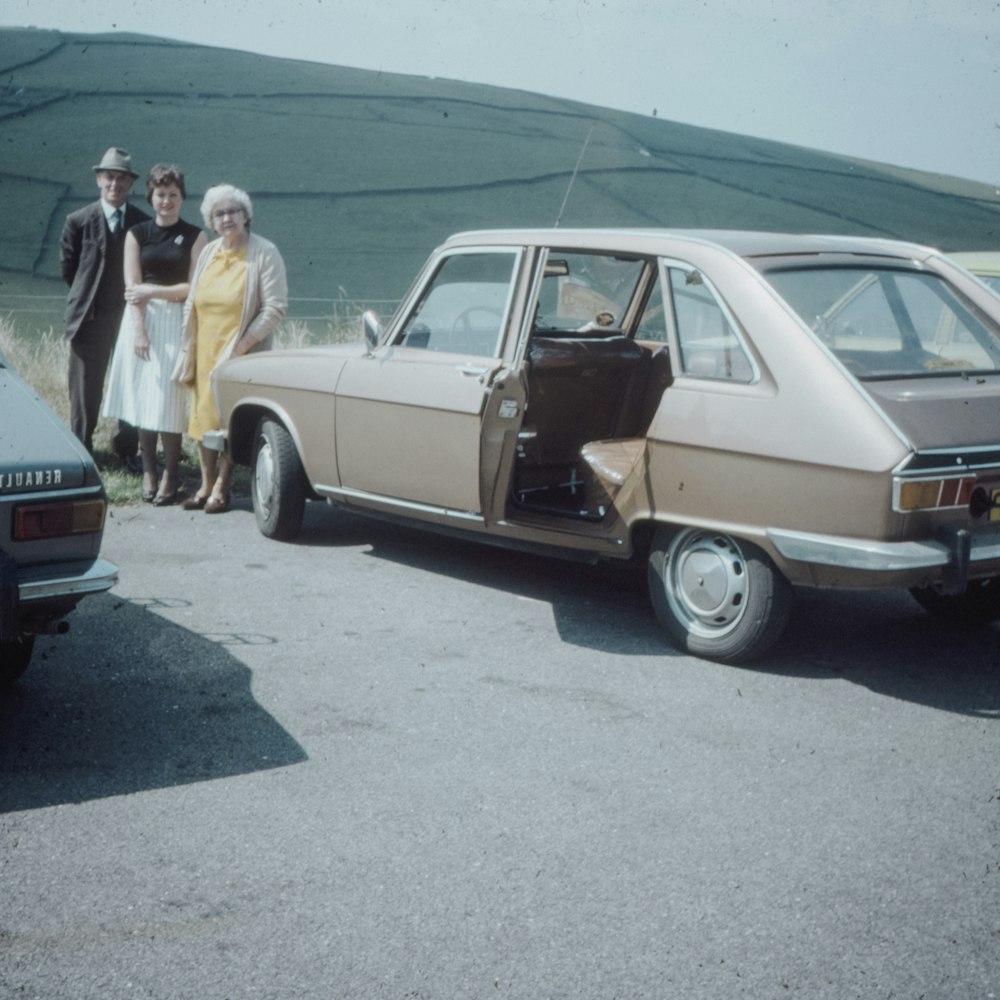 people standing beside vintage brown coupe during daytime