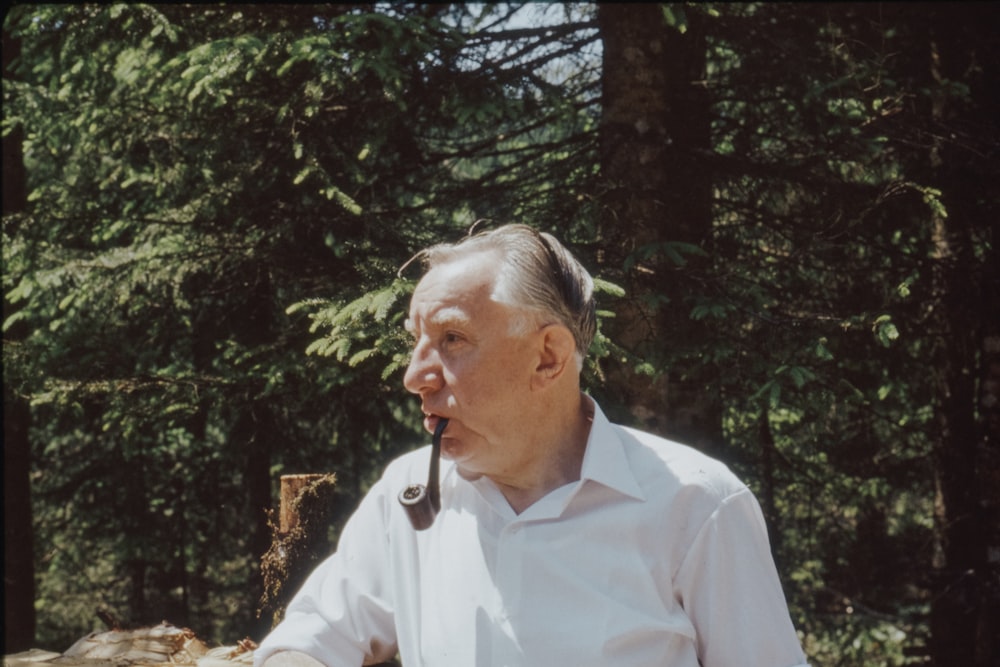 man in white dress shirt standing near green trees during daytime