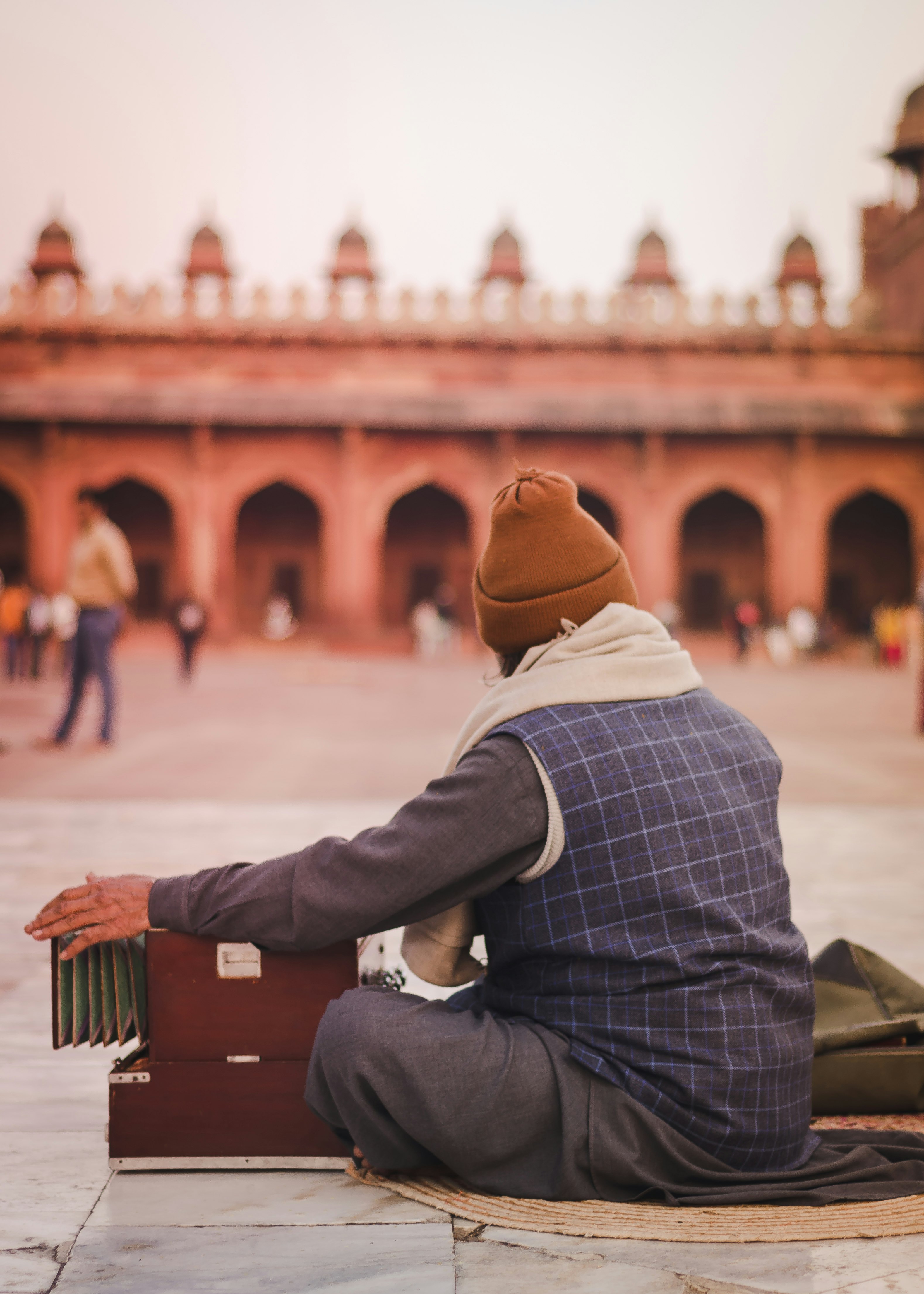 man in white and black checkered dress shirt and brown fedora hat sitting on brown wooden