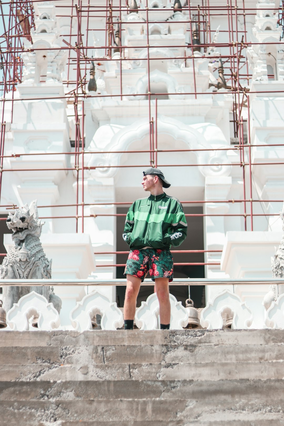 man in green and black plaid dress shirt standing in front of white concrete building during