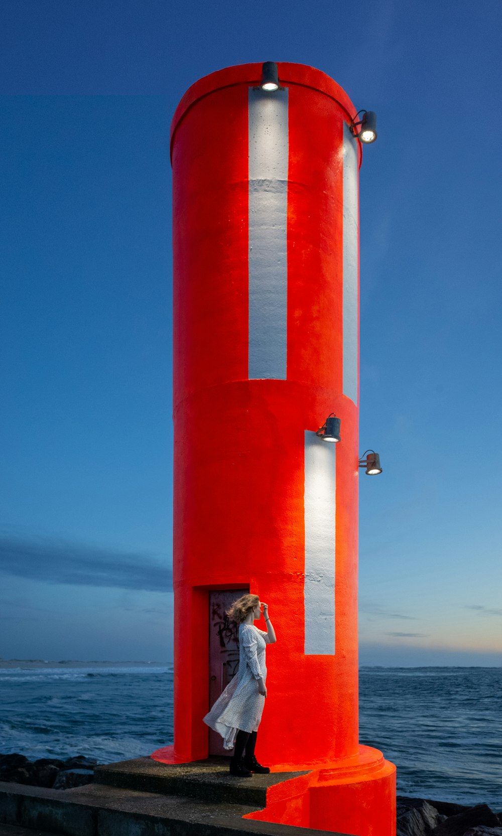 man in white shirt and blue denim jeans standing on red concrete post during daytime