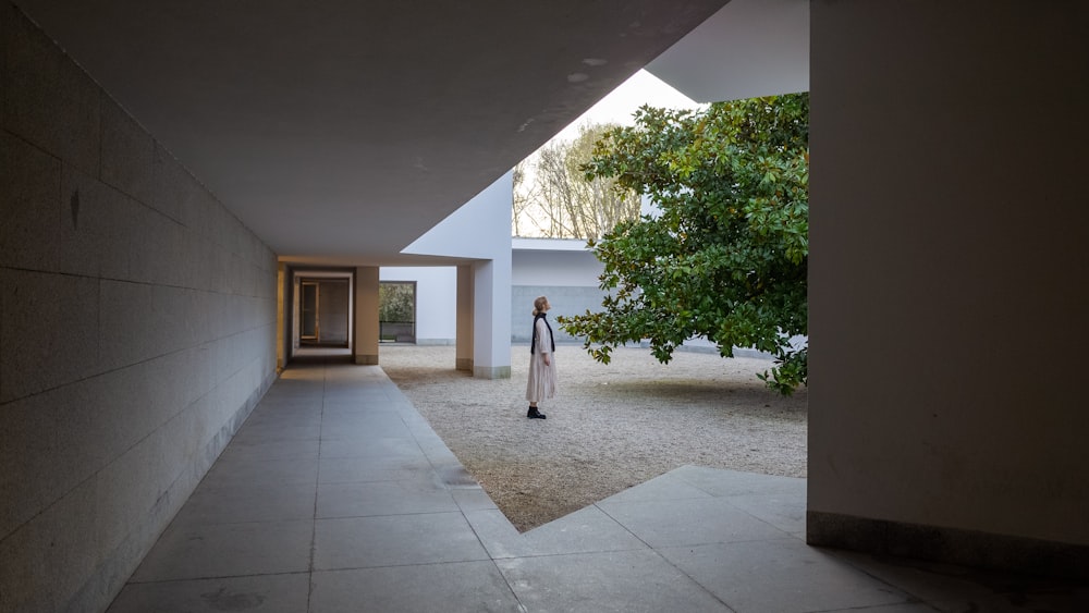 woman in white dress walking on white floor tiles during daytime