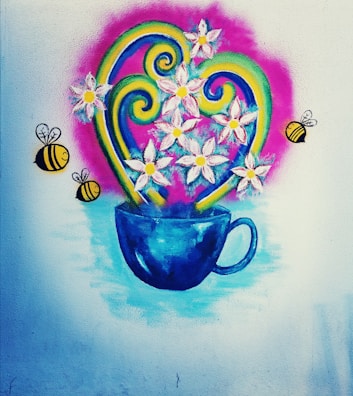 A colorful wall mural features a vivid blue cup filled with white flowers. Yellow bees with black stripes are flying around the flowers. Swirling green and yellow decorative elements add to the lively composition, all set against a pink backdrop with a soft blue base.
