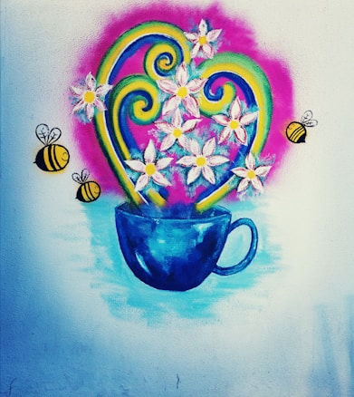 A colorful wall mural features a vivid blue cup filled with white flowers. Yellow bees with black stripes are flying around the flowers. Swirling green and yellow decorative elements add to the lively composition, all set against a pink backdrop with a soft blue base.