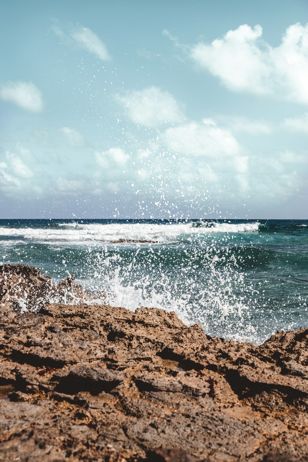 playa de arena marrón bajo el cielo azul y nubes blancas durante el día