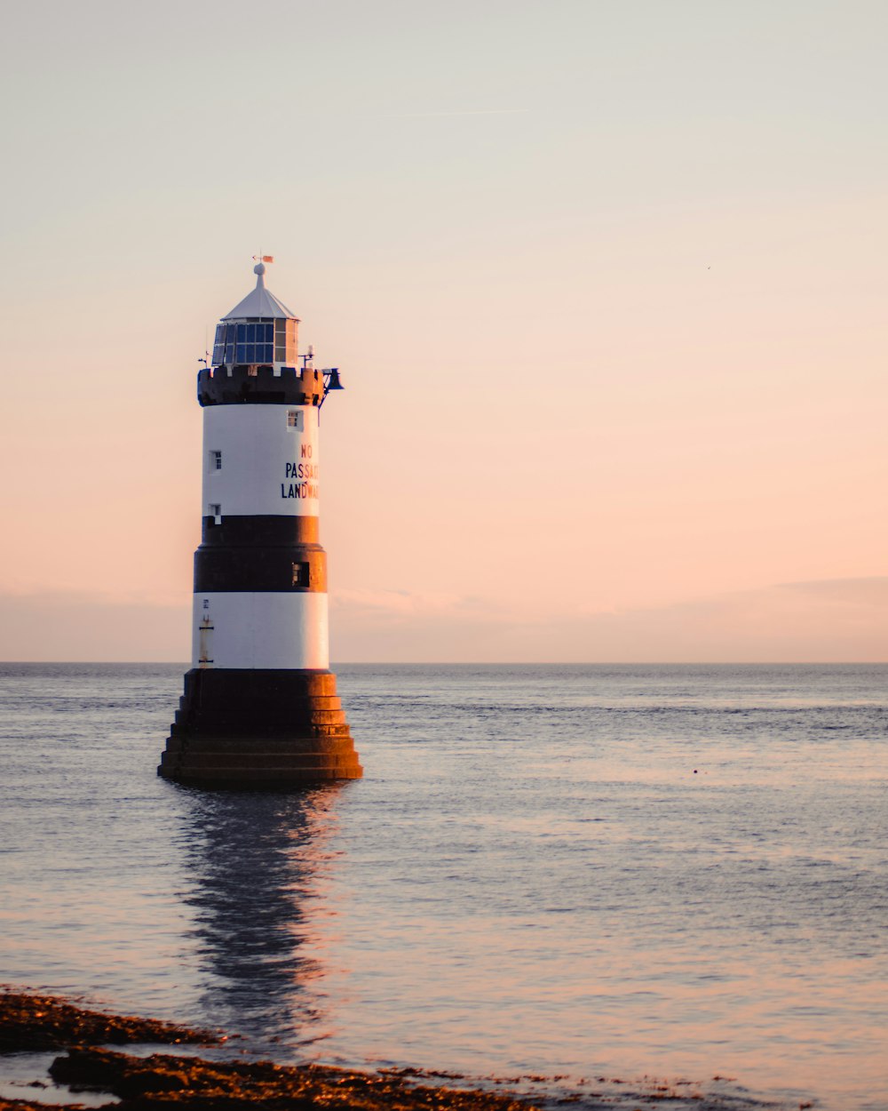 white and brown lighthouse on sea shore during sunset