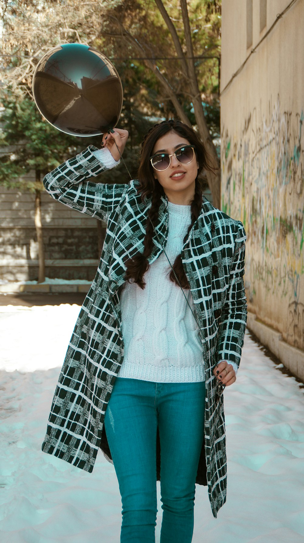 woman in black and white plaid coat and blue denim jeans wearing brown sun hat