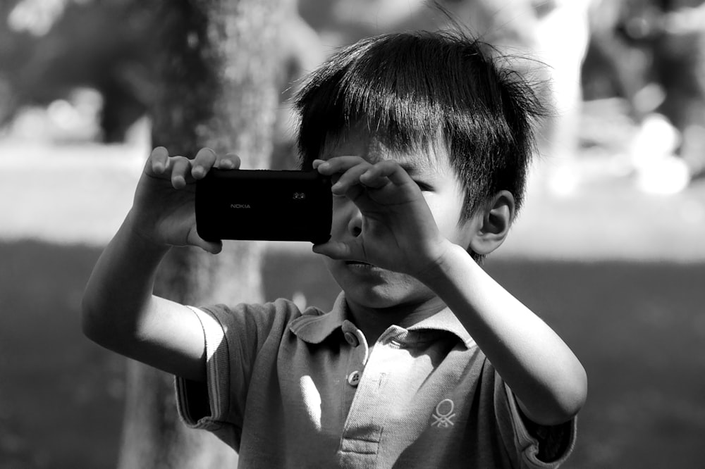 grayscale photo of boy holding camera