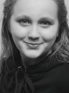 A serene black-and-white portrait of a person wearing a hoodie, eyes focused, embodying quiet confidence.