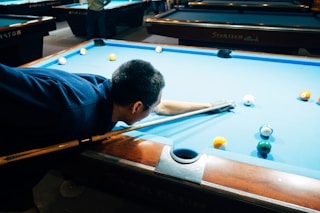 man in blue shirt playing billiard