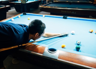 man in blue shirt playing billiard