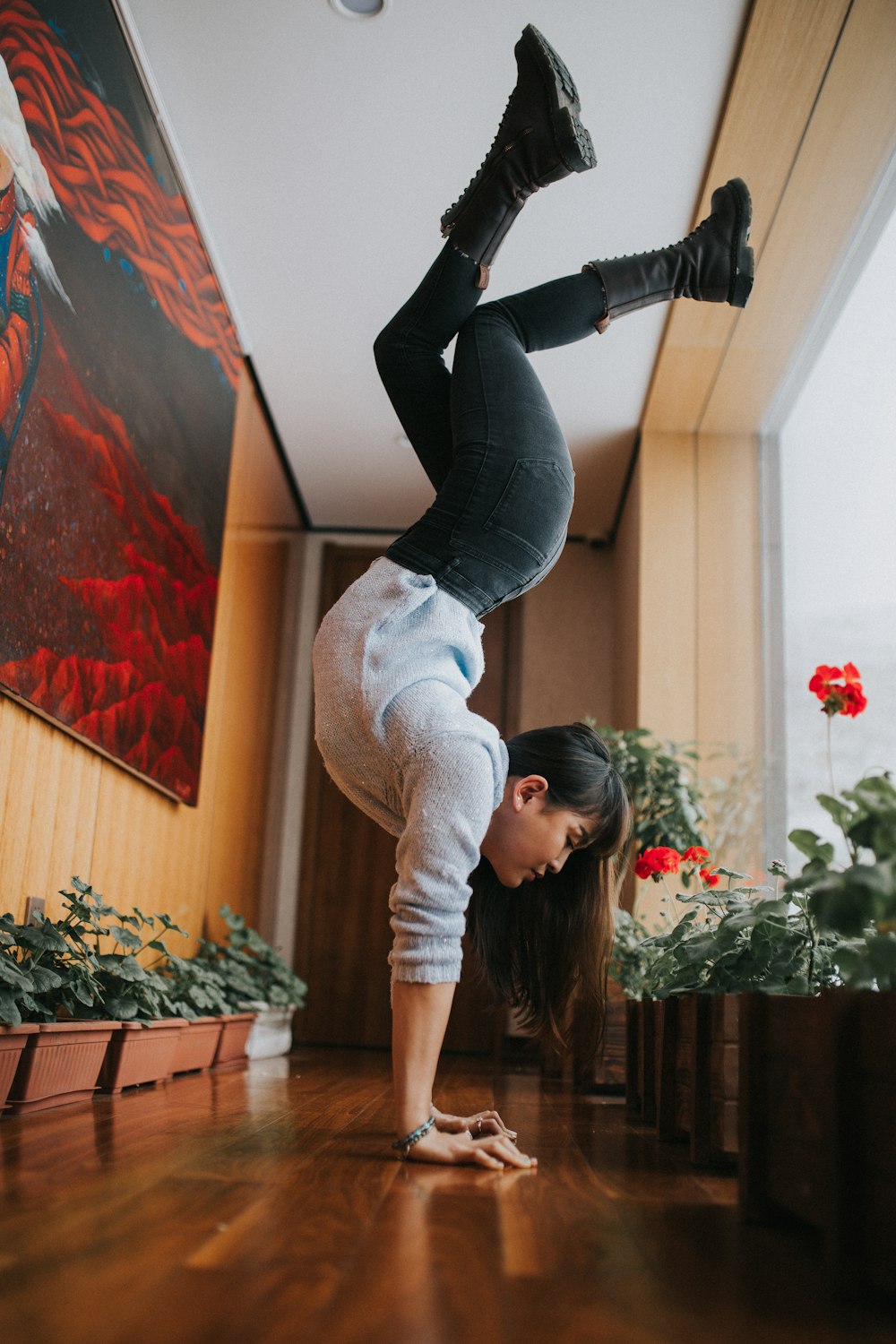 woman in gray long sleeve shirt and black pants bending her body on brown wooden floor