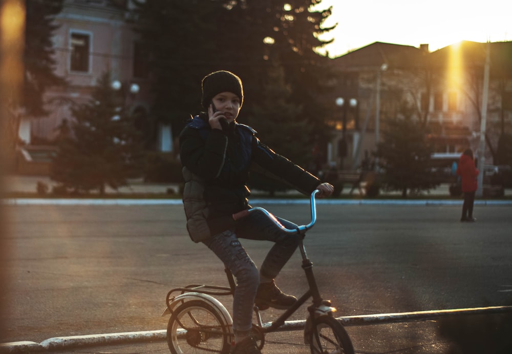 girl in black jacket riding on bicycle during daytime
