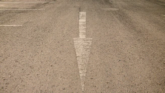 Wide angle of a striped commercial driveway with white arrows and markings.