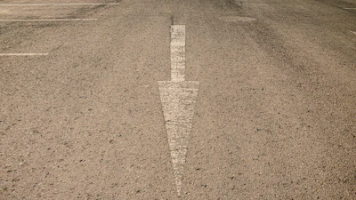 Wide angle of a striped commercial driveway with white arrows and markings.