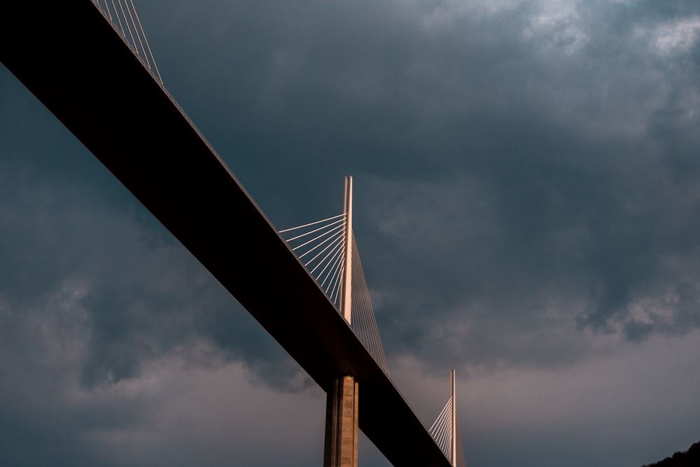 low angle photography of bridge under cloudy sky