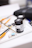 Various art supplies are arranged on a white surface, including black poster color jars, paintbrushes with orange handles, and an eraser. The background is softly blurred, indicating a creative workspace.
