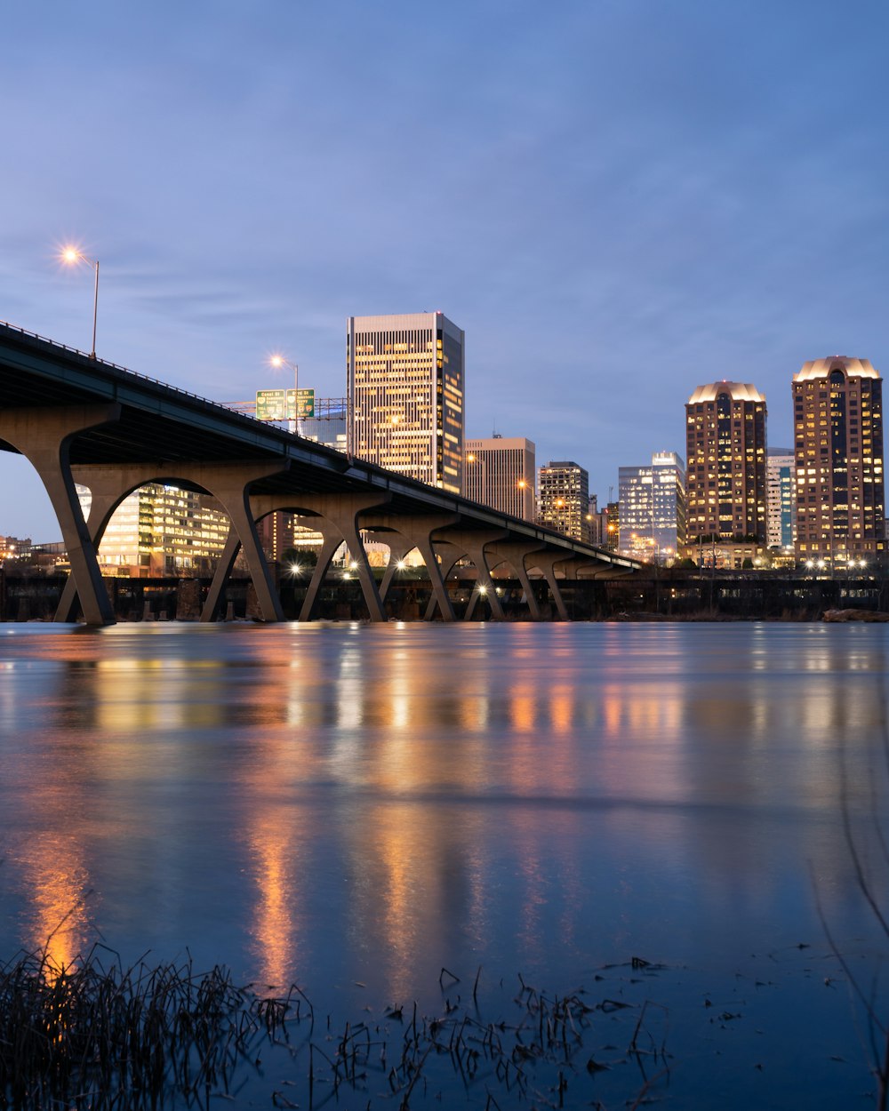 bridge over water near city buildings during night time