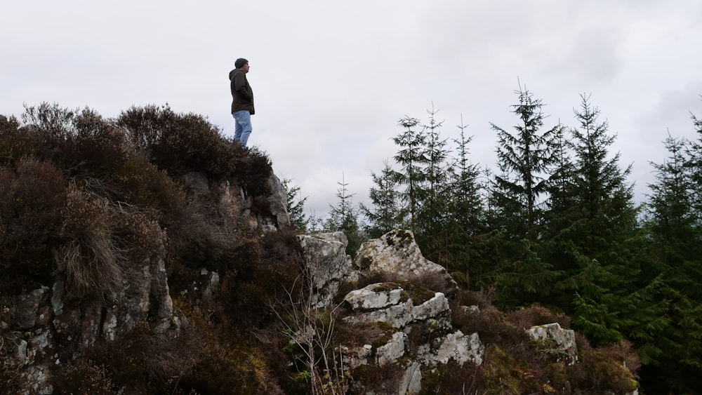 man in black jacket standing on rock formation during daytime