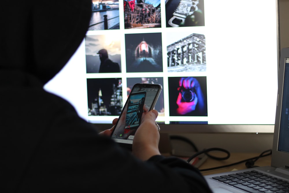 person holding black smartphone near black computer keyboard