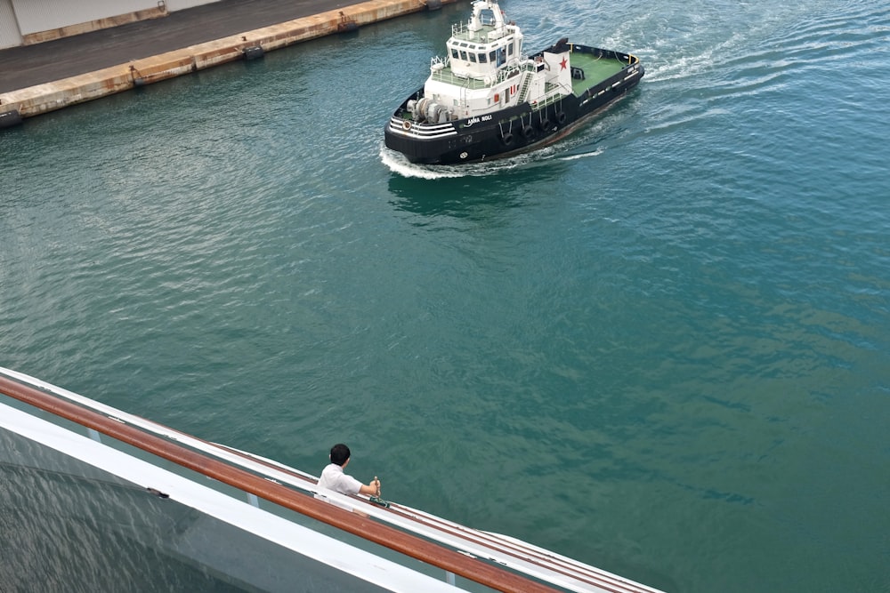 man in white shirt sitting on white and black boat during daytime