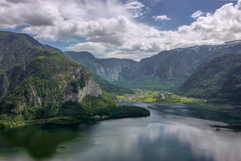 green mountains beside river under white clouds and blue sky during daytime