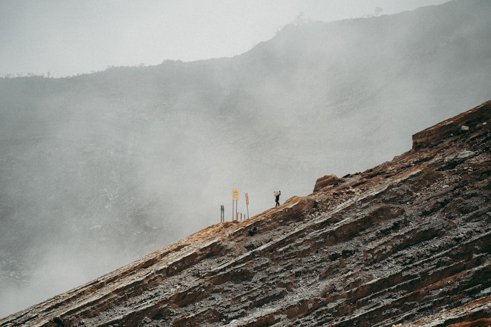 Persona in piedi sulla montagna rocciosa marrone durante il giorno