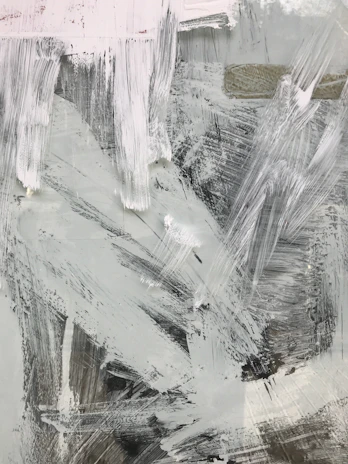 A tall vertical painting with bold, sweeping strokes of charcoal and white, framed by generous white space.