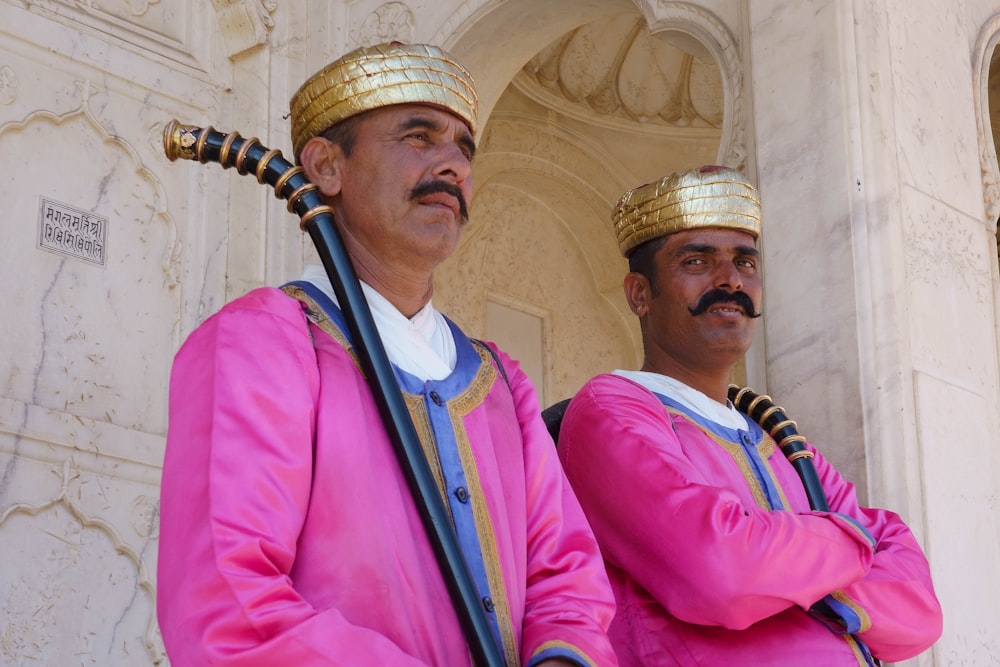 man in pink dress shirt beside man in white and black stripe shirt