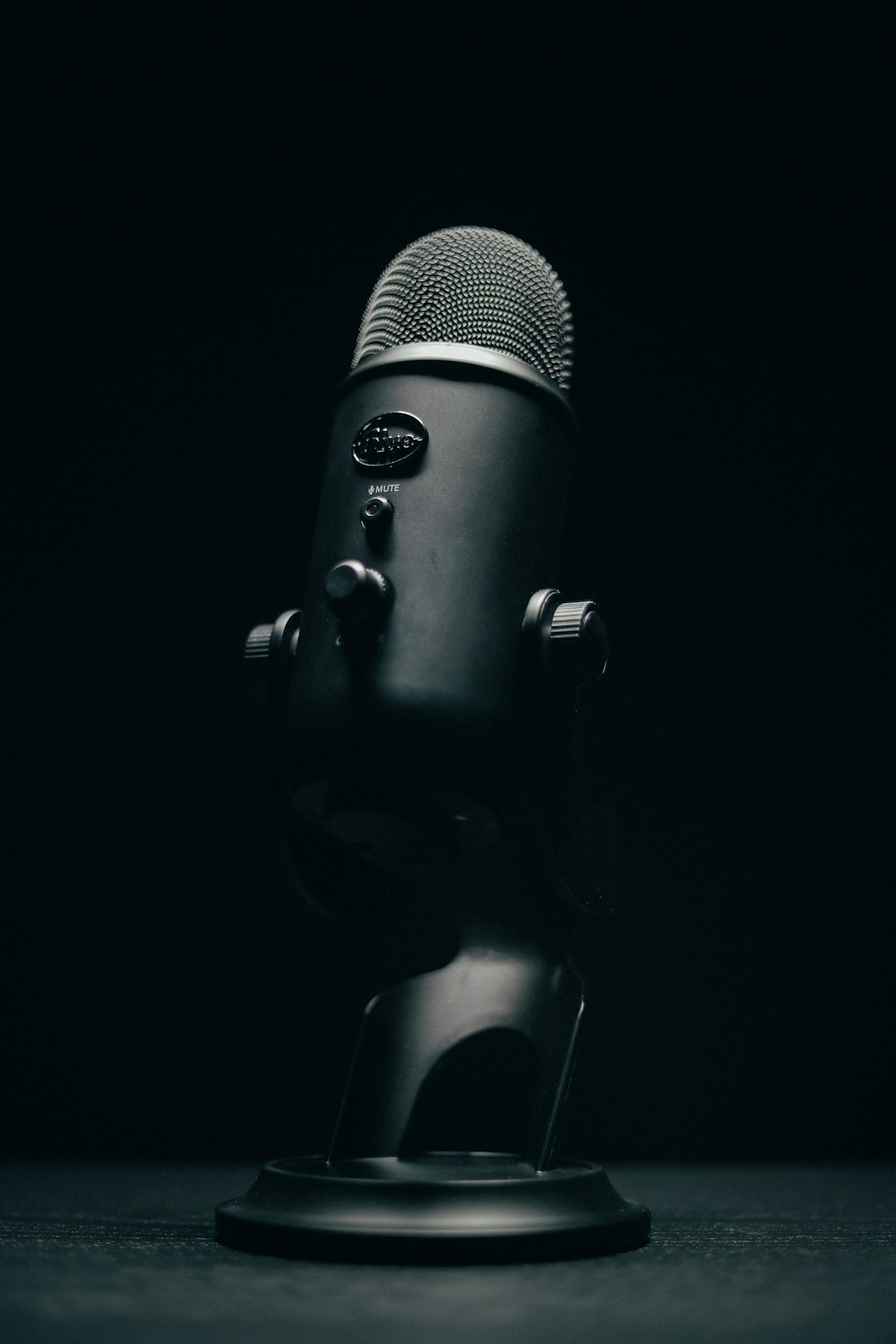 Microfono nero con supporto su sfondo nero