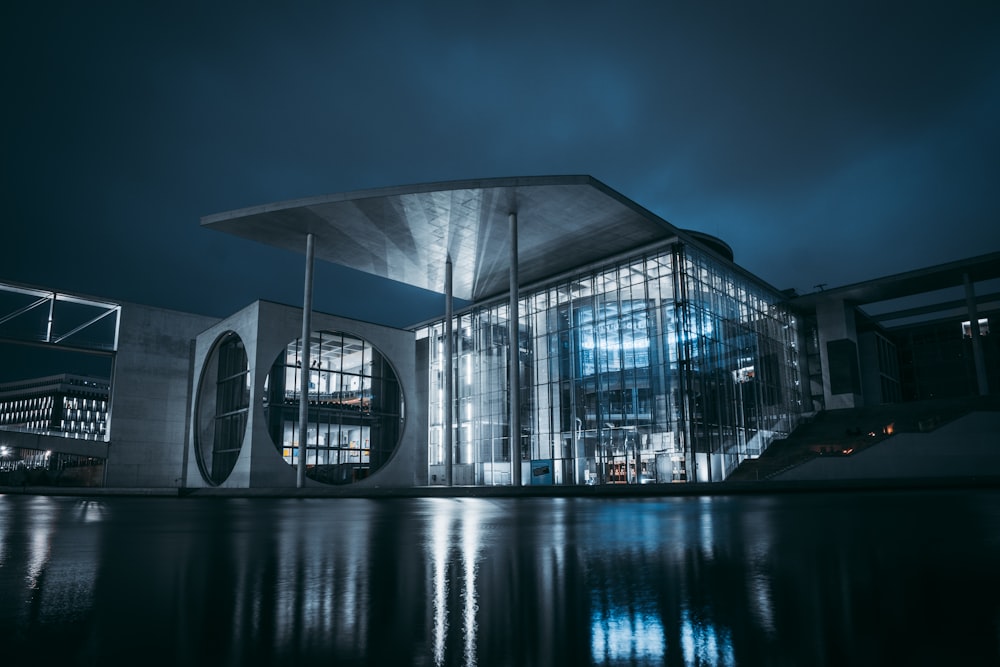 edificio bianco e grigio vicino allo specchio d'acqua durante la notte