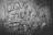 A map is overlaid with bold, black graffiti text obscuring many of the details beneath. The image is monochromatic, enhancing the contrast between the map's fine lines and the thick strokes of the graffiti.