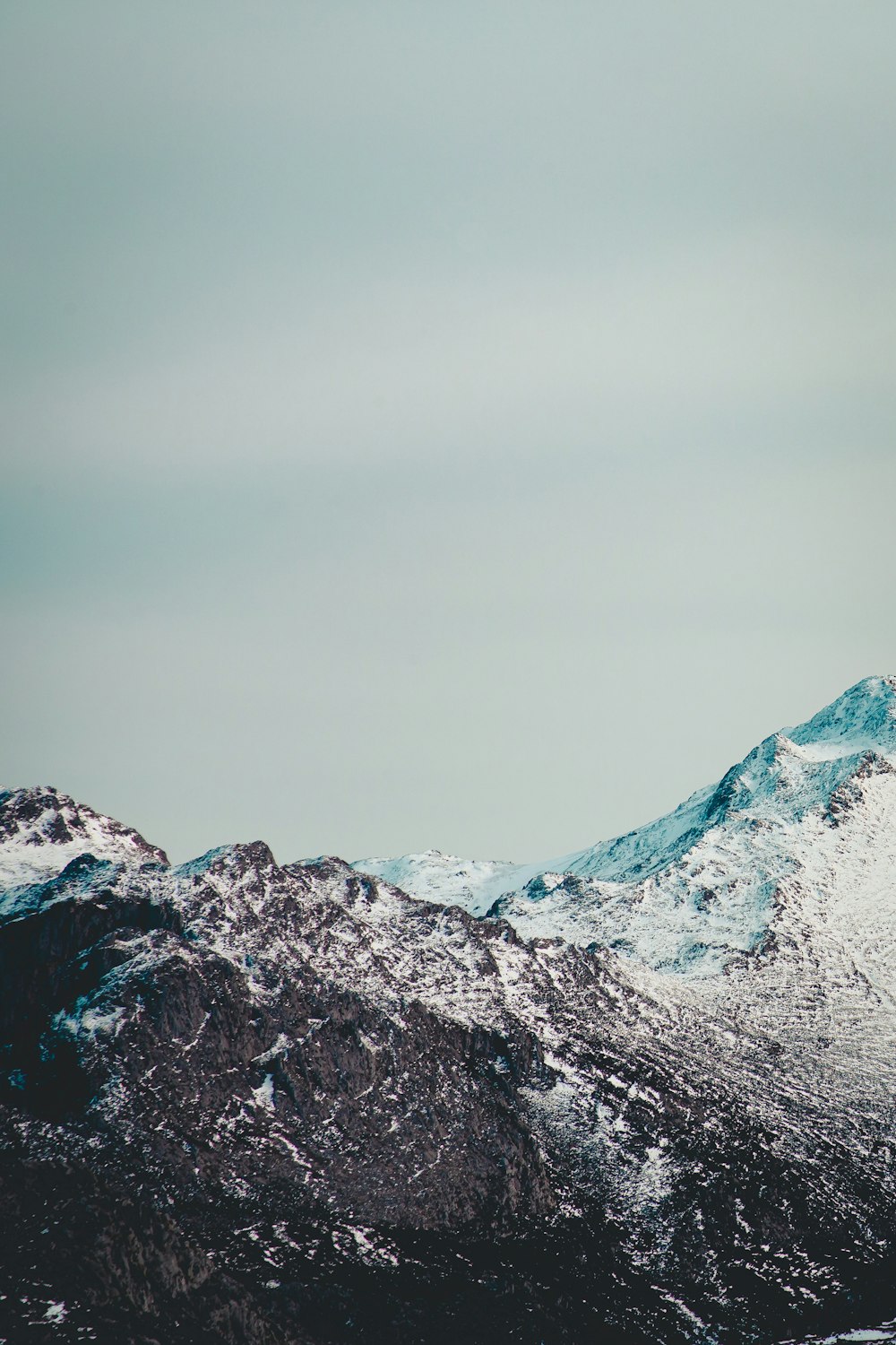 snow covered mountain under gray sky