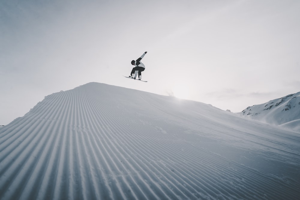 person jumping on snow covered ground during daytime