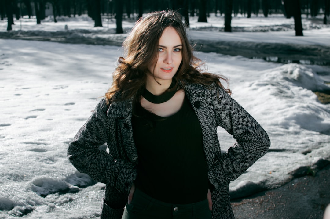 woman in black shirt and gray coat standing on snow covered ground during daytime