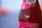 Close-up of a chilled pink lemonade bottle with condensation droplets on a sunny wooden table.