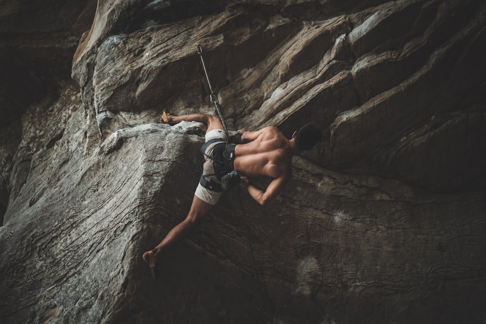 man in blue shorts climbing on brown rock