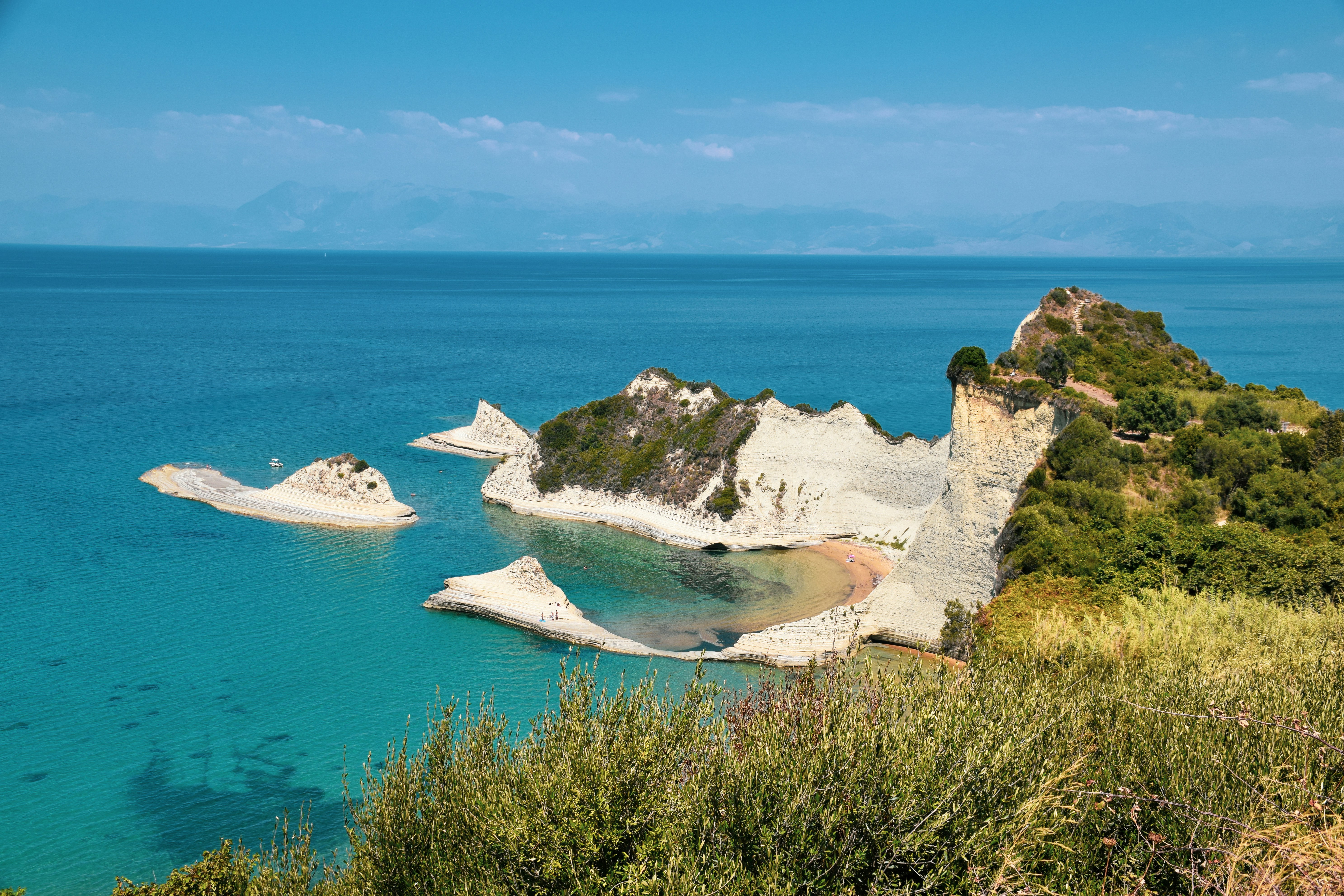 white and brown rock formation on blue sea under blue sky during daytime