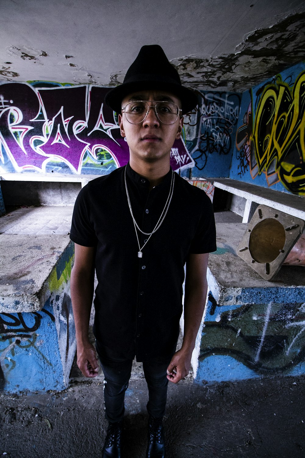 man in black polo shirt standing near graffiti wall