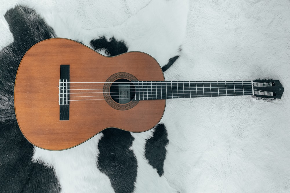 brown acoustic guitar on white and black textile