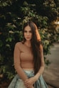 woman in brown long sleeve shirt standing near green tree during daytime