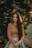 woman in brown long sleeve shirt standing near green tree during daytime